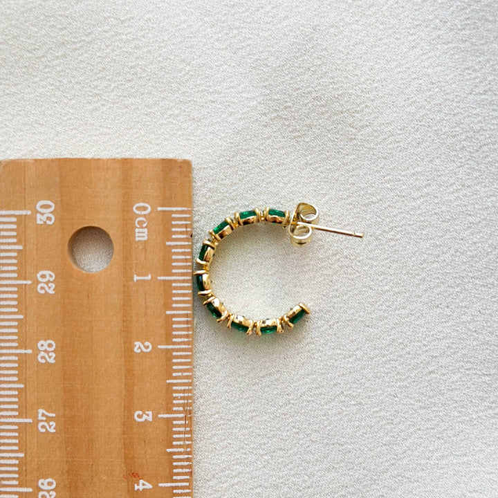  Small, huggie style hoop earring in gold, encrusted with emerald green CZ stones. 