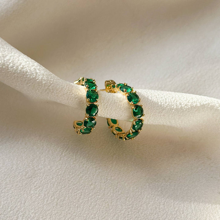  Small, huggie style hoop earring in gold, encrusted with emerald green CZ stones. 