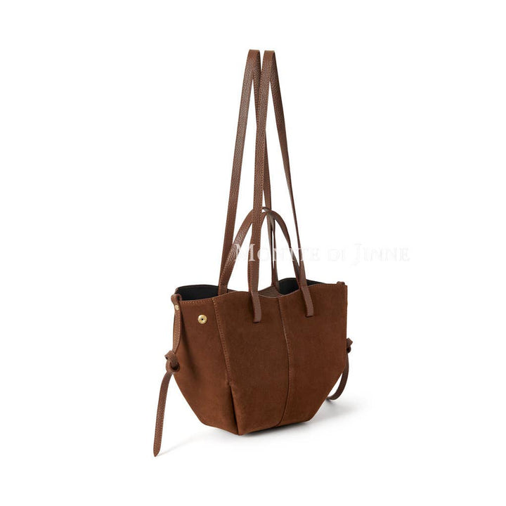 Studio image of suede tote bag showing extension of shoulder straps