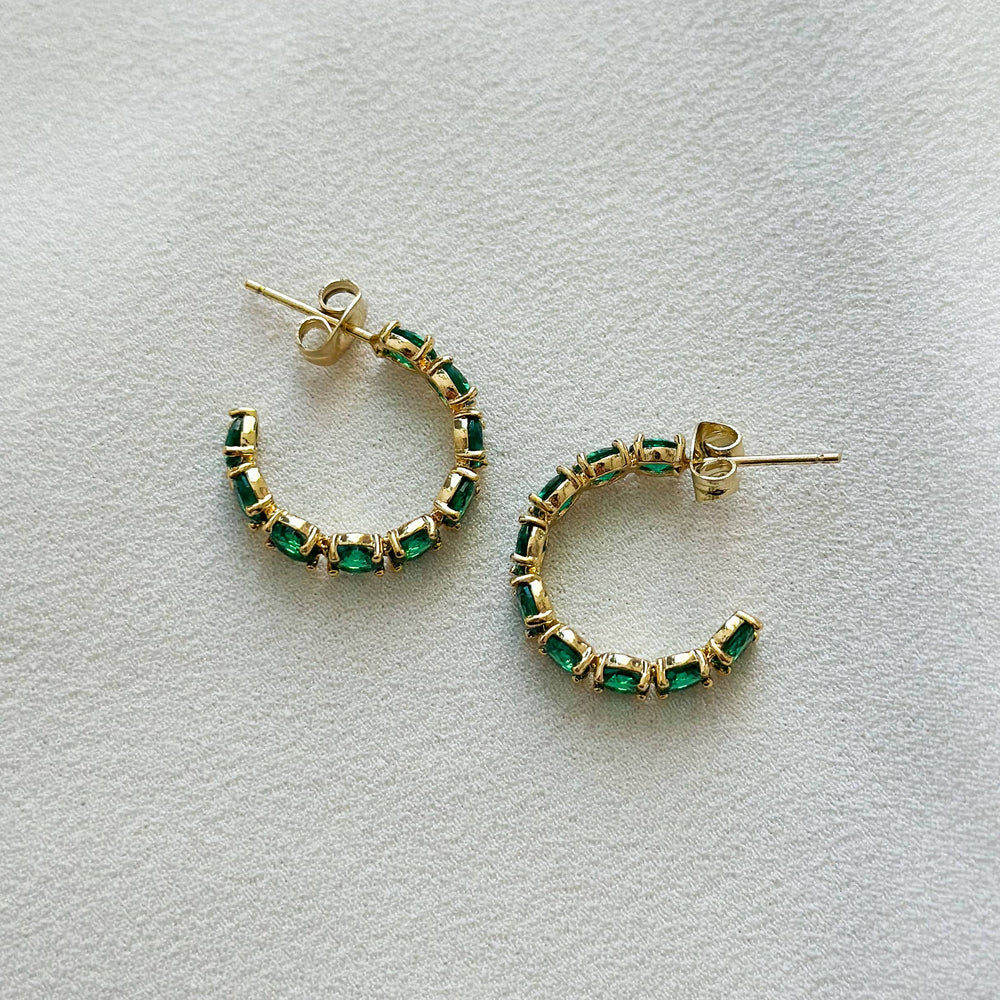  Small, huggie style hoop earring in gold, encrusted with emerald green CZ stones. 