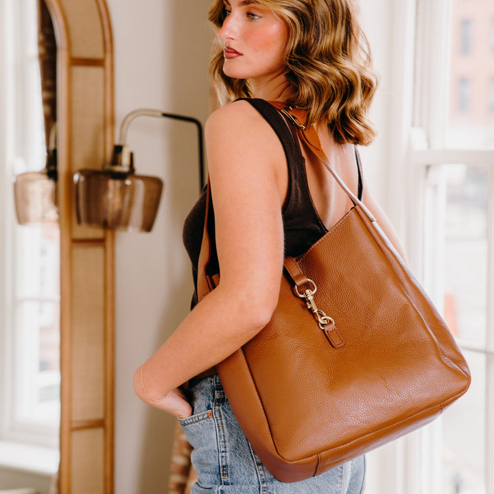 Tan leather hobo shoulder bag with hold hardware on model