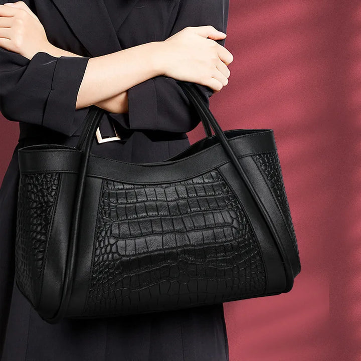 The Megyn Tote Bag in Black is an East/West style featuring rolled top grab handles and seamed detail.