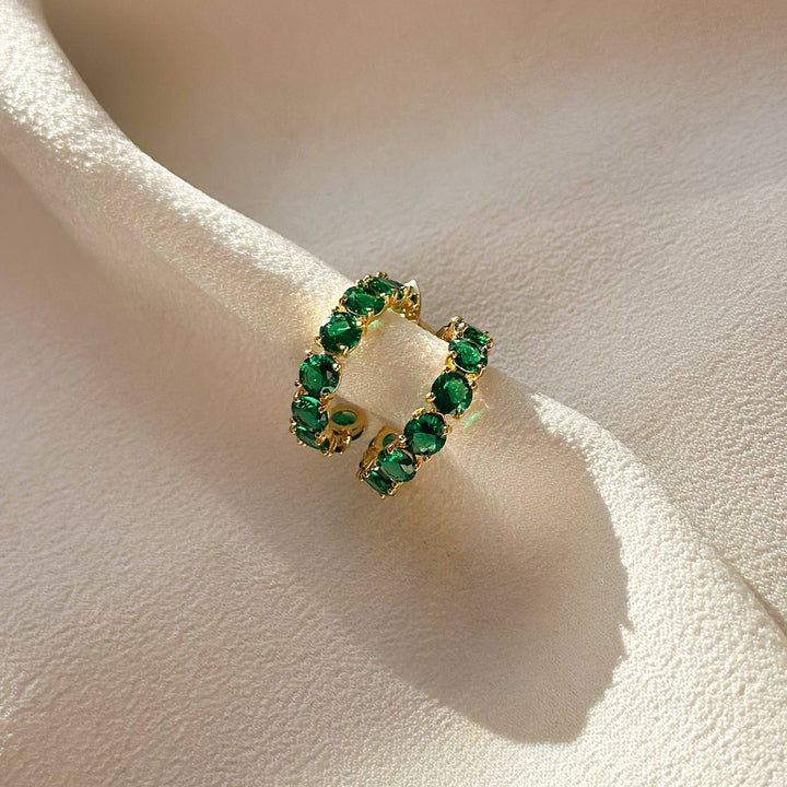  Small, huggie style hoop earring in gold, encrusted with emerald green CZ stones. 