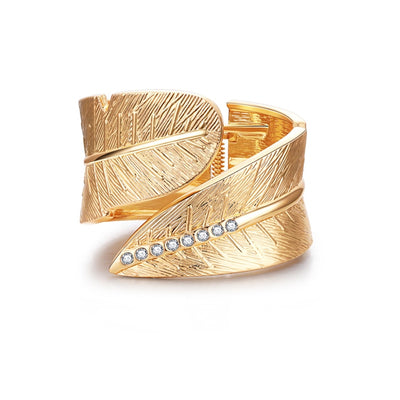 The stunning Faye cuff features a beautiful wrap-around textured leaf design with diamante stones set into the vein. Hinged/will adjust to fit.  Gold plated zinc alloy. Presented in velvet pouch.